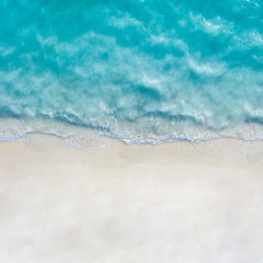 Summer seascape beautiful waves, blue sea water in sunny day. Top view from drone. Sea aerial view, amazing tropical nature background. Beautiful bright sea with waves splashing and beach sand concept