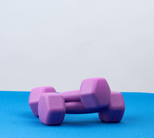 Pair Of Purple Plastic Dumbbell For Sports On A Blue Rug