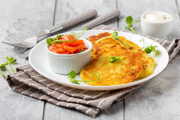 Canvas Print - Fried potato pancakes with salmon and sour cream, fritter, roesti, golden crispy crust. Traditional delicious food