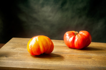 still life with 2 juicy ripe tomatoes on a wooden table.