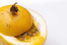 Close Up Of Passion Fruit With Its Top Cut Off And Half Covering The Inside With Its Juicy Yellow Pulp And Black Seeds Going Over The Rim 