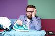 © koldunova - Unhappy bearded man with glasses is ironing clean linen on the board, he is tired of housework and looks sadly at the camera.