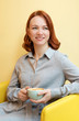 © Anastasiia - Young woman with a smile in a cafe with a Cup of coffee. A sunshine yellow background.
