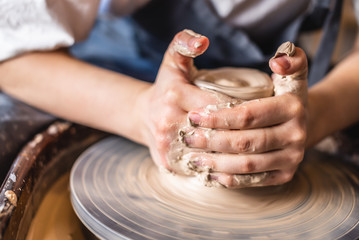 Potter working on a Potter's wheel making a vase. Woman forming the clay with hands creating jug in a workshop. Close up