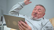 © iaginzburg - Man lie on the bed in the hospital and talk agressively on tablet
