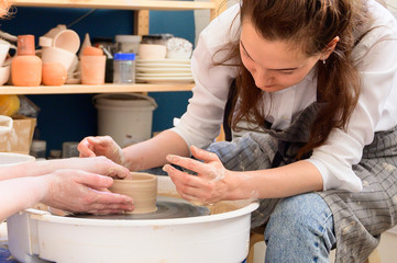 Woman working with clay during pottery workshop on potter's wheel