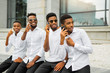 © Alexandr - four handsome young african men in white shirts with phones in their hands