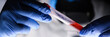 Male chemist hand in blue protective gloves hold test tube closeup background