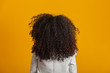 © Brastock Images - Young black woman on her back with afro hairstyle on yellow background. Girl with african hairstyle. Studio shot.