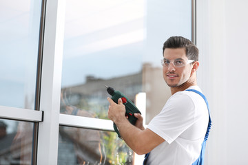 Wall Mural - Construction worker repairing plastic window with electric screwdriver indoors