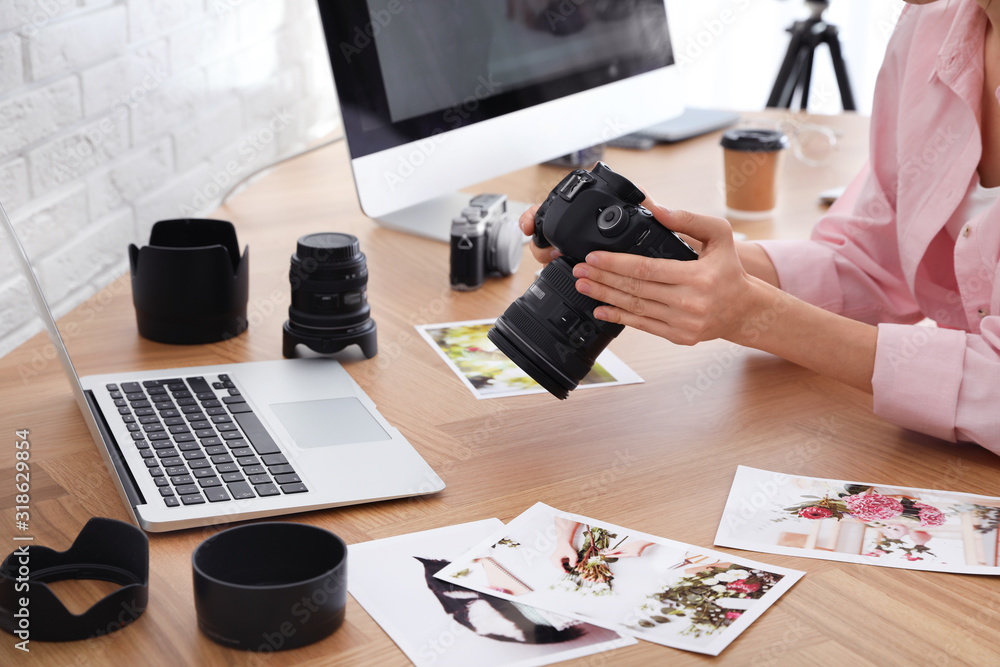 Professional photographer with camera working at table in office, closeup - obrazy, fototapety, plakaty 