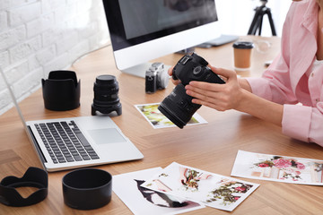 Wall Mural - Professional photographer with camera working at table in office, closeup