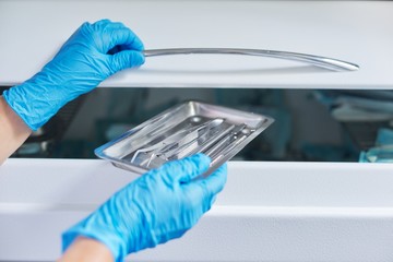 Female nurse doing sterilization of dental medical instruments in autoclave