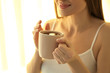© New Africa - Young woman with cup near window at home, closeup. Lazy morning