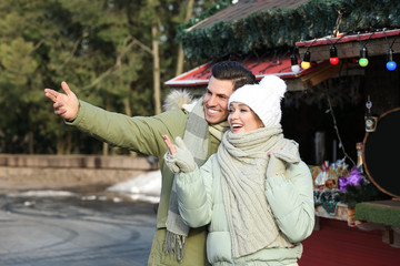 Poster - Happy couple in warm clothes at winter fair. Christmas season