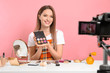 © New Africa - Beauty blogger filming make up tutorial on pink background