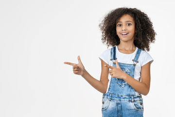 Adorable cute african little girl pointing on copy space in studio white background