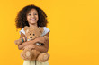 © InsideCreativeHouse - Little cute african girl hugging teddy bear toy isolated on yellow background