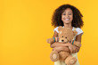 © InsideCreativeHouse - Portrait of smiling african girl hugging teddy bear toy isolated on yellow background