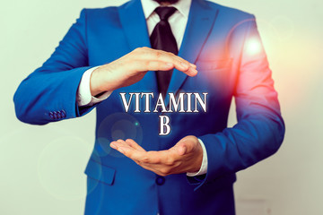 Conceptual hand writing showing Vitamin B. Concept meaning Nutrient that helps keep the body nerve and blood cells healthy Man in front of table. Mobile phone and notes on the table