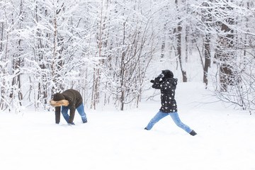 Lifestyle, season and leisure concept - Funny couple playing snowball in winter park