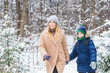 © satura_ - Parenting, fun and season concept - Happy mother and son having fun and playing with snow in winter forest