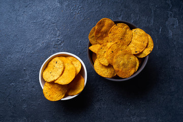  Mexican round-shaped nacho chips in two bowls. Top view chips on dark background with copy space