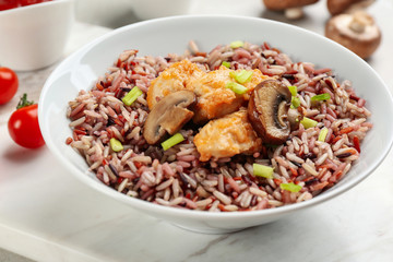 Tasty brown rice with chicken and mushrooms on table, closeup