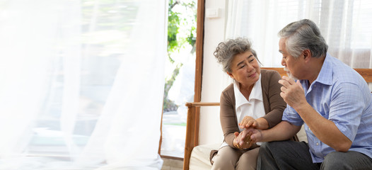 Asian senior retired couple holding hands and take care together at home, Alzheimer disease or suffering with dementia concept