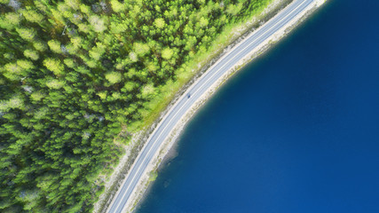 Wall Mural - Aerial view of the road near lake. Travelling on the motorcycle. Landscape with transport from drone. View at the road and lake from air