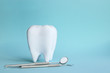 White tooth with dental instruments on a blue background in honor of the international day of the dentist on February 9