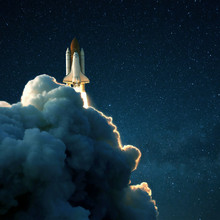 Space Rocket Launches Into Space Against A Starry Blue Sky. Ship Shuttle With Clouds Of Smoke