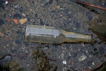 Canvas Print - High angle shot of a dirty glass bottle thrown on the ground