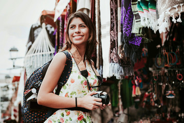 Wall Mural - hispanic woman backpacker holding a camera in a traditional mexican Market in Mexico, Vacations