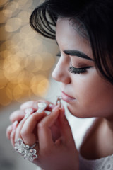 The bride touches her lips to the ring. Beautiful bride with professional make up and hairstyle. Preparing the bride for the upcoming wedding. Sexy bride. Sexy girl. Happiest bridal day. 