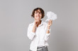 Pensive young business woman in white shirt posing isolated on grey background. Achievement career wealth business concept. Mock up copy space. Hold say cloud with lightbulb, put hand prop up on chin.