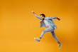 Cheerful young bearded man in casual blue shirt posing isolated on yellow orange background studio portrait. People lifestyle concept. Mock up copy space. Jumping with outstretched hand like Superman.