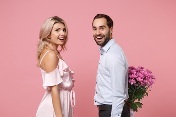 Wall Mural - Side view of excited couple two guy girl in party outfit celebrating isolated on pastel pink background. People lifestyle Valentine's Day Women's Day birthday holiday concept. Hold bouquet of flowers.