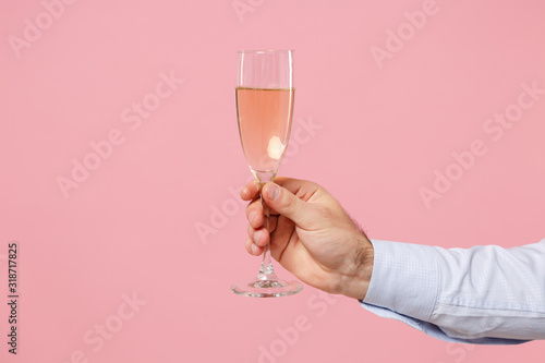 Fotomural Close up cropped photo of male hold in hand glass of champagne isolated on pastel pink wall background