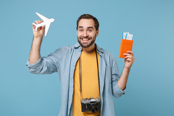 Wall Mural - Smiling traveler tourist man in casual clothes with photo camera isolated on blue background. Passenger traveling abroad on weekends. Air flight journey. Hold passport boarding pass tickets air plane.