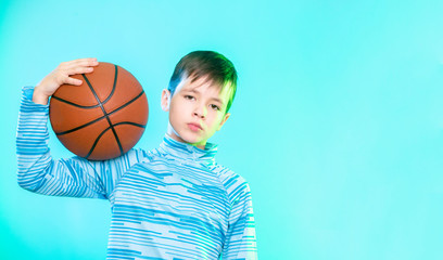 Wall Mural - Young basketball player posing with a ball in his hand isolated on blue background.