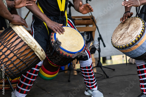 Fotomural Closeup of three artist performing traditional colorful string wrapped african d
