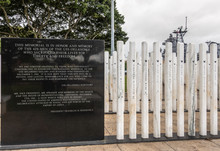 Oahu, Hawaii, USA. - January 10, 2020: Pearl Harbor, Group Of White Name Sticks And Black Marble Slab With Texts At USS Oklahoma Memorial. Green Foliage And Gray Sky In Back. 