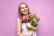 © Богдан Маліцький - young beautiful girl with a bouquet of flowers on a colored pink background, a woman holds tulips and smiles