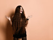 Female with long hair in brown turtleneck, short skirt, nylon tights. Laughing, gesticulating posing on beige background. Close up