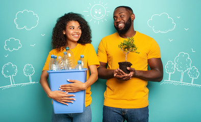 Wall Mural - Happy couple hold a plastic container with bottles and a small tree over a light blue color. Concept of ecology, conservation, recycling and sustainability