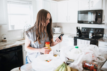 Lifestyle of women unloading her groceries at home in a white kitchen