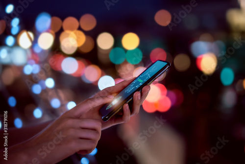 Fotografía Close-up of hands scanning fingerprint on smartphone to unlock mobile phone on bokeh colors light in night atmospheric city, Concept security in identity technology