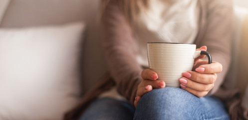 Poster - Cup of hot coffee in female hands, home comfort concept