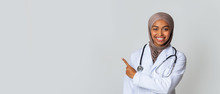 Black Female Doctor In Headscarf Indicating Copy Space On Light Background
